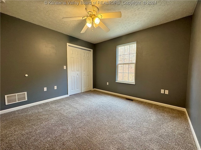 unfurnished bedroom with carpet, ceiling fan, a textured ceiling, and a closet