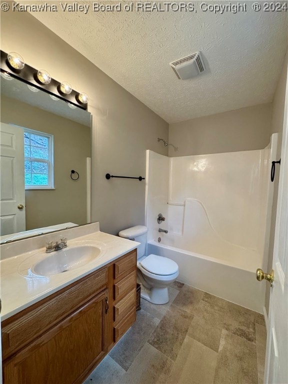 full bathroom with vanity, a textured ceiling, toilet, and shower / washtub combination