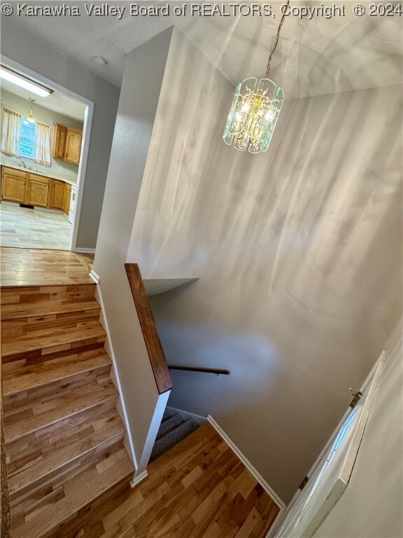 staircase featuring hardwood / wood-style flooring and a notable chandelier