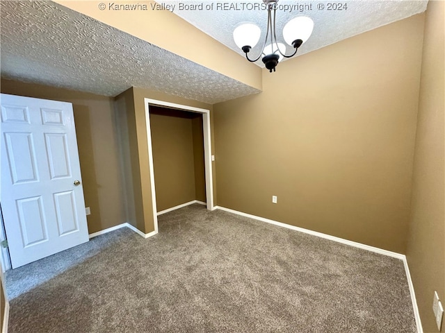 carpeted spare room with a textured ceiling and a notable chandelier