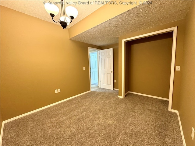 unfurnished bedroom featuring carpet, a textured ceiling, and a chandelier