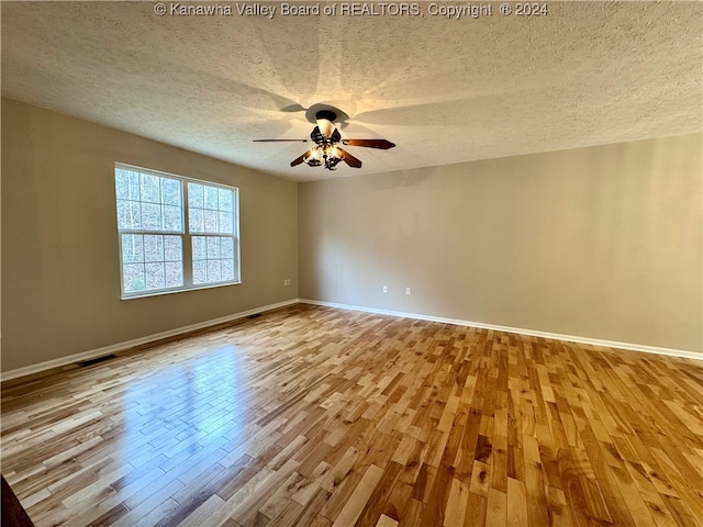 unfurnished room with a textured ceiling, light hardwood / wood-style flooring, and ceiling fan