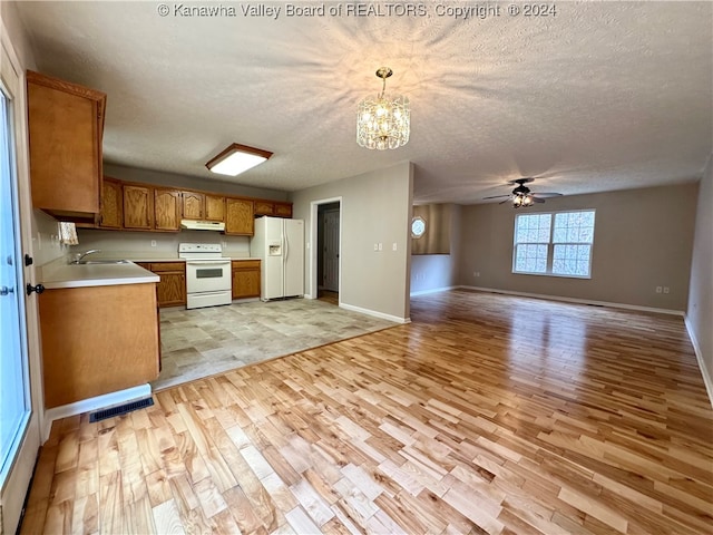 kitchen with decorative light fixtures, light hardwood / wood-style floors, white appliances, and a textured ceiling