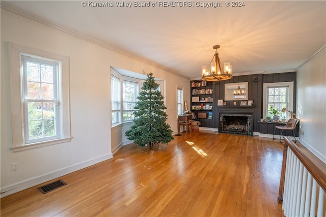 unfurnished living room featuring an inviting chandelier, wood-type flooring, and ornamental molding