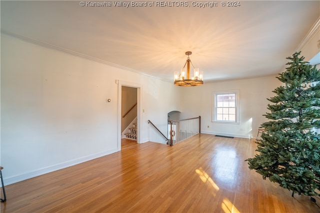 spare room featuring a notable chandelier, crown molding, and light hardwood / wood-style flooring