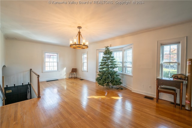 interior space with ornamental molding, an inviting chandelier, a healthy amount of sunlight, and light hardwood / wood-style floors