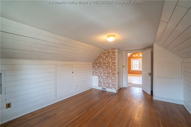 additional living space featuring wood walls, dark hardwood / wood-style flooring, and lofted ceiling