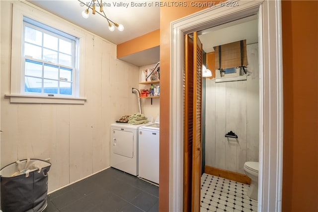 laundry area featuring washer and dryer, a chandelier, and wooden walls