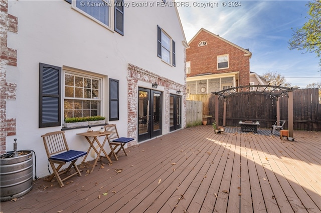 wooden terrace with a pergola, french doors, and a fire pit