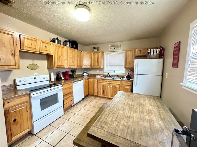 kitchen with a textured ceiling, sink, light tile patterned floors, and white appliances