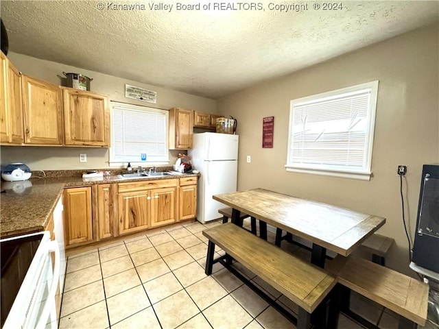 kitchen with a textured ceiling, sink, light tile patterned floors, and white appliances