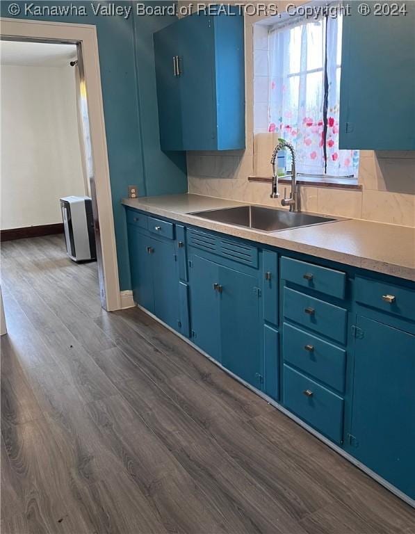 kitchen with blue cabinetry, sink, and dark wood-type flooring