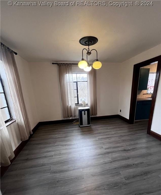 unfurnished dining area with dark hardwood / wood-style floors and an inviting chandelier