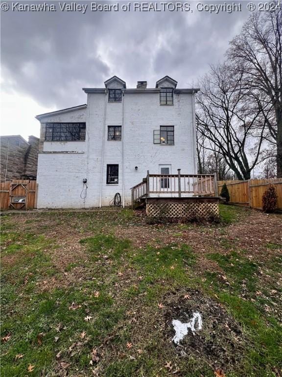 back of property with a lawn and a wooden deck