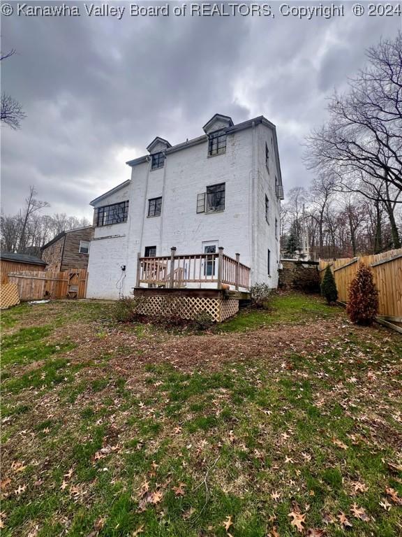 back of house featuring a lawn and a wooden deck