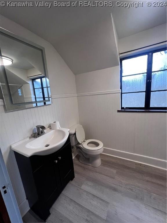 bathroom with hardwood / wood-style flooring, vanity, toilet, and vaulted ceiling