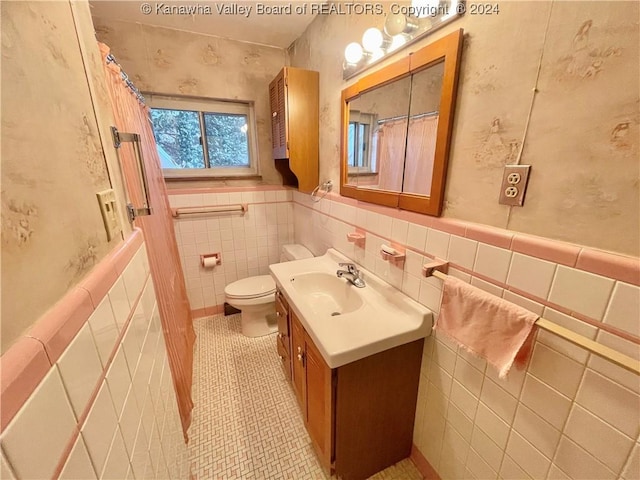 bathroom with tile patterned flooring, vanity, tile walls, and toilet