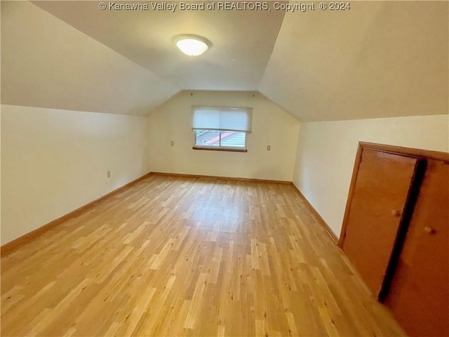 additional living space with light hardwood / wood-style floors and lofted ceiling