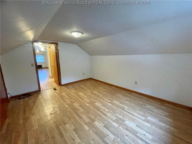 additional living space with light hardwood / wood-style flooring and lofted ceiling