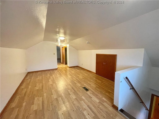 additional living space with light hardwood / wood-style floors and vaulted ceiling