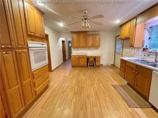 kitchen with white appliances, a baseboard heating unit, sink, ceiling fan, and light hardwood / wood-style floors