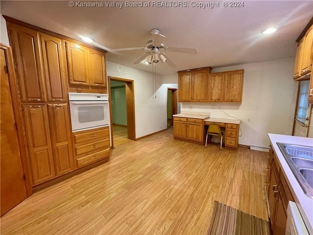 kitchen with oven, sink, ceiling fan, light wood-type flooring, and baseboard heating