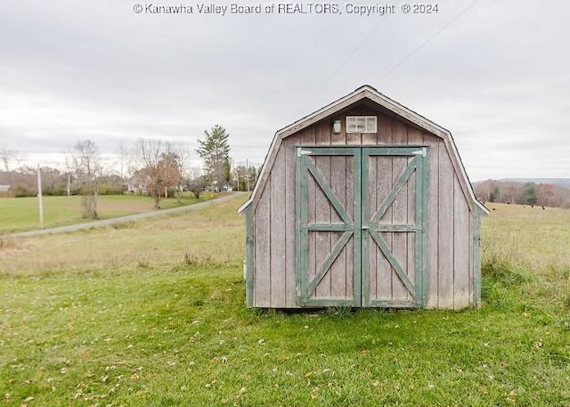 view of outbuilding featuring a rural view and a yard