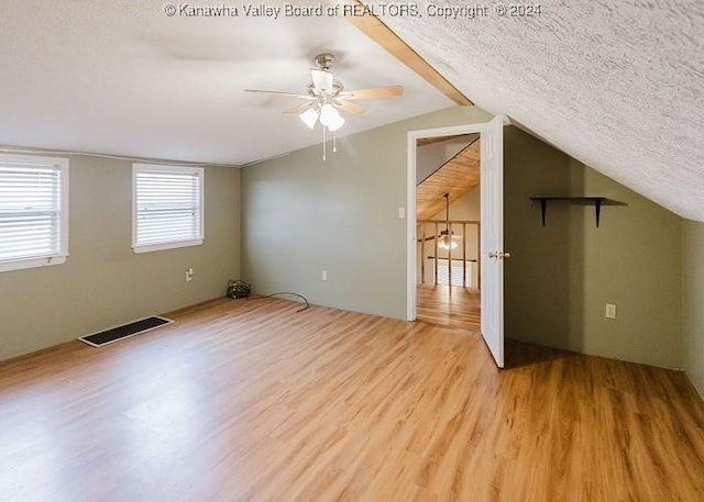 bonus room with a textured ceiling, light wood-type flooring, ceiling fan, and lofted ceiling