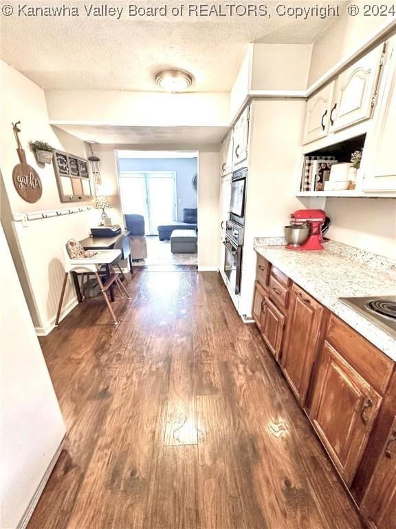 kitchen featuring black electric stovetop, a textured ceiling, dark wood-type flooring, and stainless steel oven