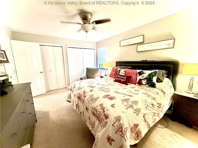 carpeted bedroom featuring ceiling fan and two closets