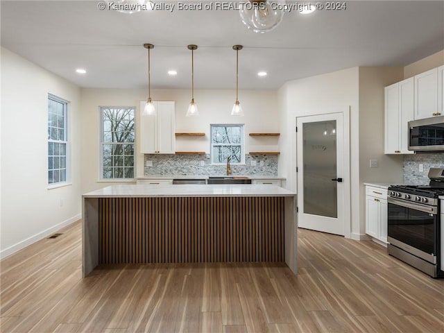 kitchen featuring white cabinets, a kitchen island, stainless steel appliances, and light hardwood / wood-style flooring