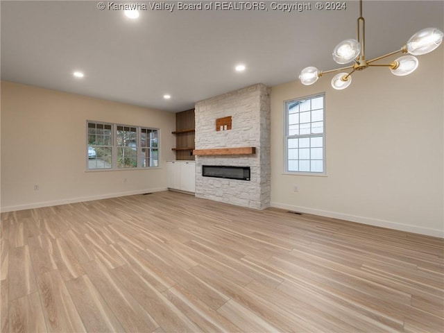 unfurnished living room featuring a chandelier, a fireplace, and light hardwood / wood-style floors