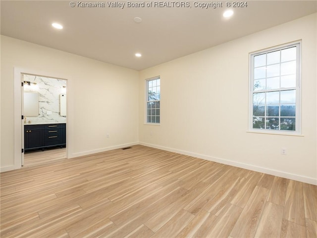 unfurnished bedroom featuring light wood-type flooring and ensuite bathroom