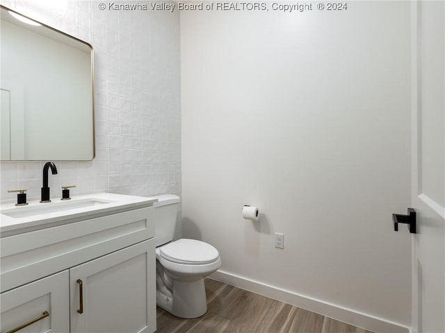 bathroom with decorative backsplash, vanity, hardwood / wood-style flooring, tile walls, and toilet