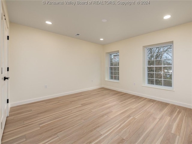 empty room with light hardwood / wood-style floors and a healthy amount of sunlight