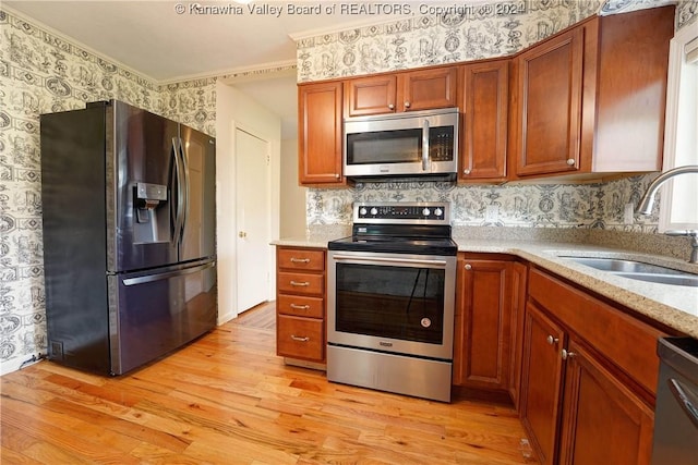 kitchen featuring sink, light hardwood / wood-style flooring, ornamental molding, appliances with stainless steel finishes, and tasteful backsplash