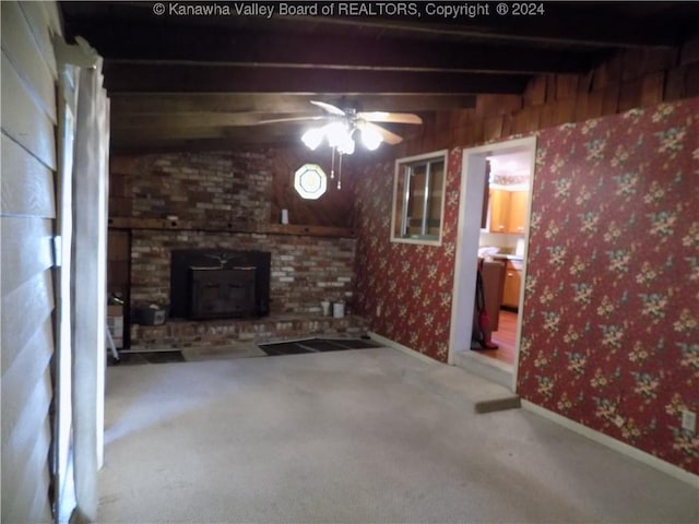 unfurnished living room featuring beamed ceiling, carpet flooring, ceiling fan, and a wood stove