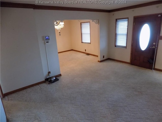 entryway featuring light carpet, a chandelier, and crown molding