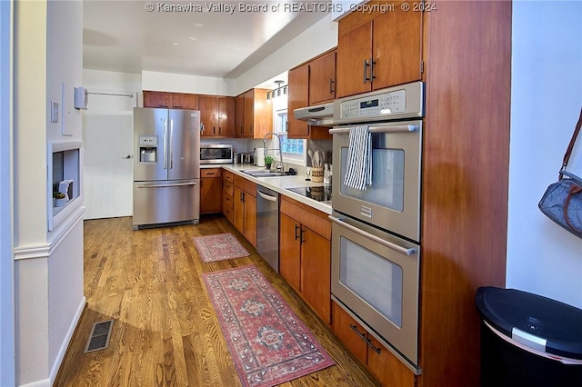 kitchen featuring appliances with stainless steel finishes, light hardwood / wood-style flooring, and sink