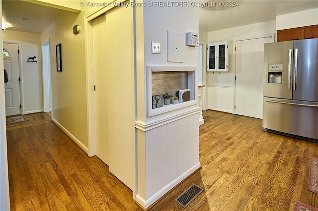 kitchen with stainless steel fridge with ice dispenser, white cabinets, and light wood-type flooring