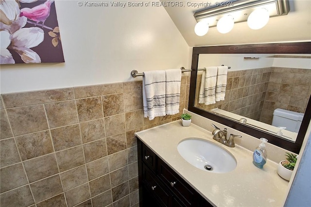 bathroom with vanity, tile walls, and toilet