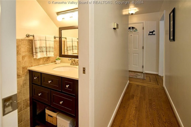 interior space featuring dark hardwood / wood-style flooring, tile walls, lofted ceiling, and sink