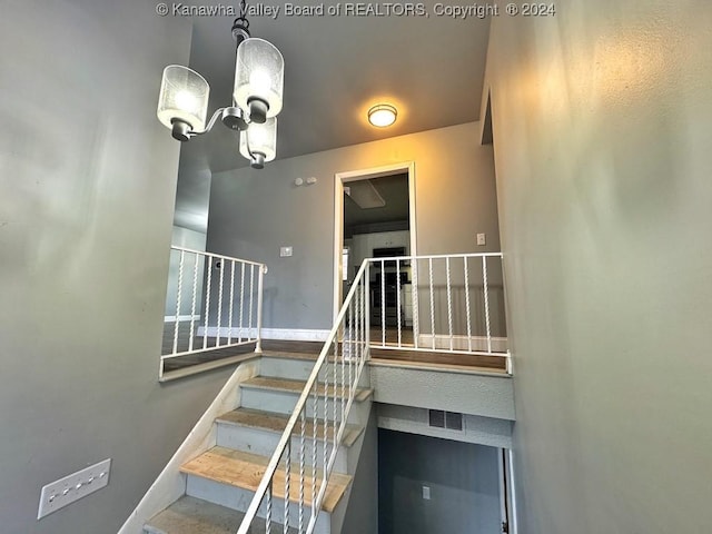 staircase with an inviting chandelier