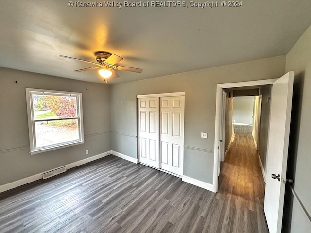 unfurnished bedroom featuring dark hardwood / wood-style floors, ceiling fan, and a closet