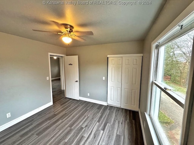 unfurnished bedroom with dark hardwood / wood-style floors, ceiling fan, and a closet