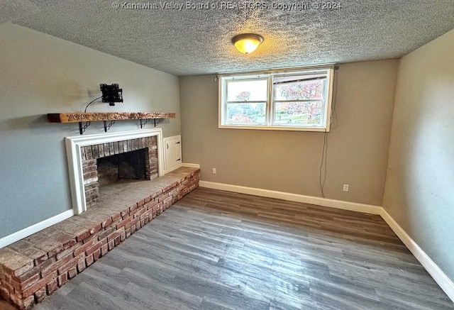 living room with hardwood / wood-style floors, a textured ceiling, and a brick fireplace