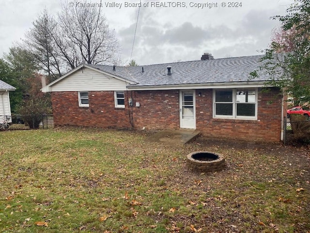 rear view of house with a yard and an outdoor fire pit