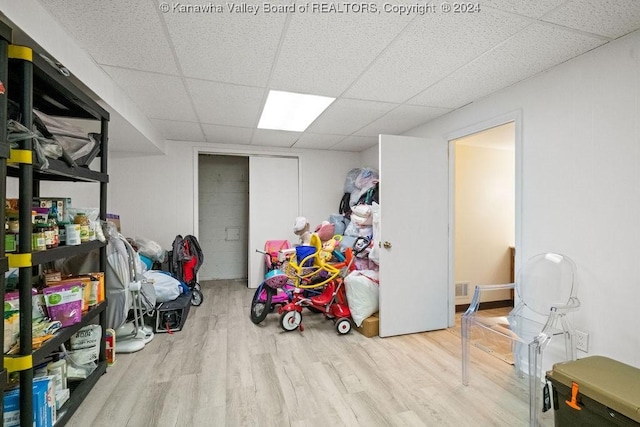 basement featuring a drop ceiling and light hardwood / wood-style floors