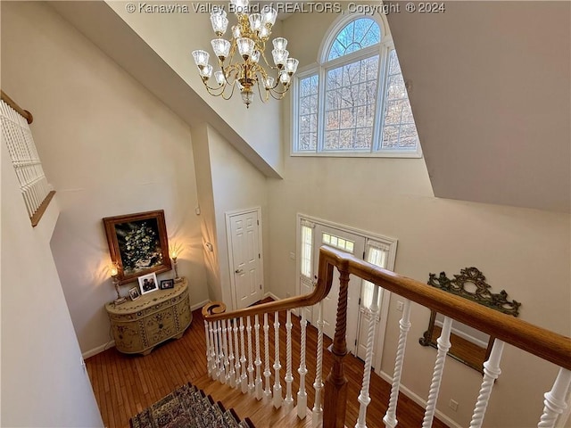 stairway featuring a chandelier, hardwood / wood-style floors, and a high ceiling