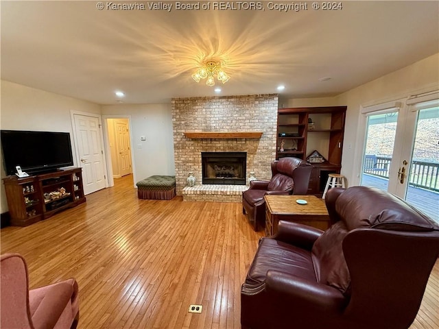 living room with wood-type flooring, french doors, and a brick fireplace